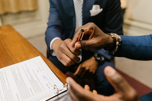 people in blue suits signing a contract